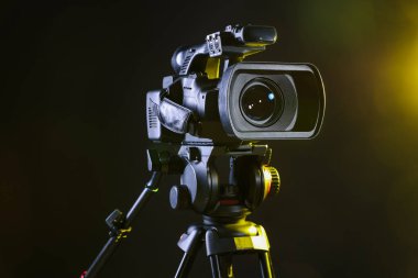 Siyah arka planda tripodu olan modern video kamera, yakın plan