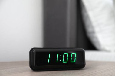 Dijital alarm saat 11 'de kapalı bir odada, komodinin yanında.