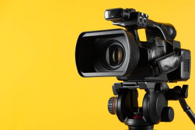 Sarı arka planda modern video kamera, yakın plan. Metin için boşluk