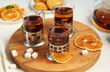 Beyaz ahşap masada servis edilen metal tutacaklı çay bardakları