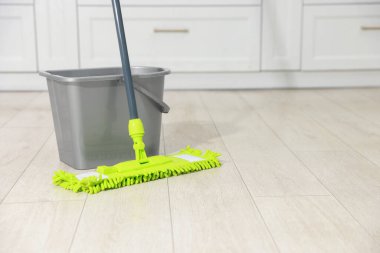 İçerideki ahşap zeminde mikrofiber paspas ve kova. Metin için boşluk