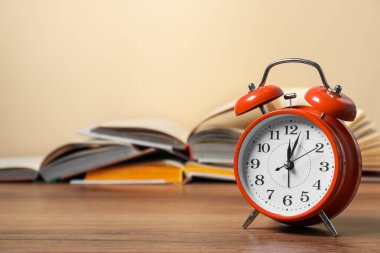 Çalar saat ve ahşap masadaki kitapları aç, yazı için yer aç. Bilgi zamanı