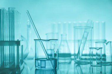 Aynanın yüzeyinde turkuaz arka plana karşı laboratuvar camı var.