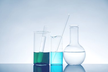 Ayna yüzeyinde ışık arkaplanına karşı sıvı bulunan laboratuvar camları