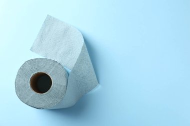 Açık mavi arka planda renkli tuvalet kağıdı rulosu, üst manzara. Metin için boşluk