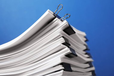 Mavi arkaplandaki kağıtların olduğu ataçlar, yakın plan. Metin için boşluk