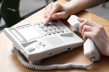 Kapalı alandaki ahşap masada telefonla arayan kadın.