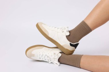 Açık kahverengi çorap giyen ve beyaz arka planda şık ayakkabılar giyen kadın, yakın plan.