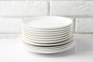 Different clean dishware on white table near brick wall
