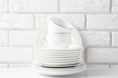 Different clean dishware on white table near brick wall