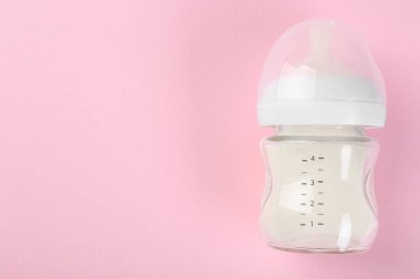 Pembe arka planda sütle beslenme şişesi, üst manzara. Metin için boşluk