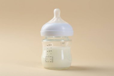 Bej arka planda sütle beslenme şişesi