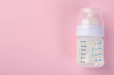Pembe arka planda sütle beslenme şişesi, üst manzara. Metin için boşluk