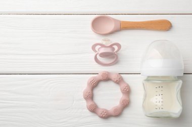 Süt, kaşık, emzik ve iple besleme şişesi beyaz ahşap masa, düz yatıyordu. Metin için boşluk