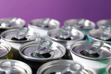 Mor arka planda birçok alüminyum içecek kutusu, yakın plan