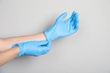 Doktor açık gri arka plana tıbbi eldiven takıyor, yakın plan. Metin için boşluk