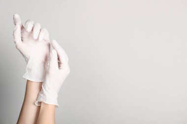 Açık gri arka planda tıbbi eldivenli doktor, yakın plan. Metin için boşluk
