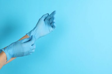 Doktor açık mavi arka plana tıbbi eldiven takıyor, yakın plan. Metin için boşluk