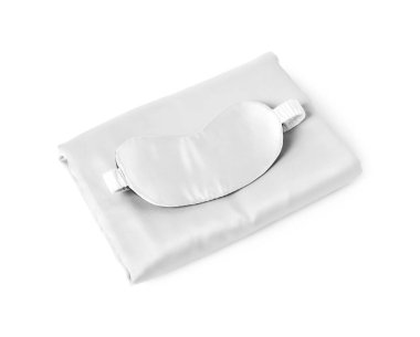 Beyaz arka planda ipek çarşaflar ve uyku maskesi.