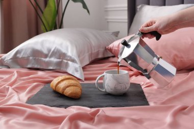 Yatağın üzerine güzel ipek çarşaflarla aromatik kahve koyan kadın, yakın plan.