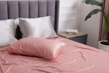 Evde ipek çarşaflı bir yatak.