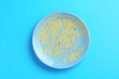 Açık mavi arka planda kirli bir tabak, üst görünüm