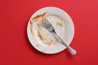 Kirli tabak ve çatal kırmızı arka plan, üst görünüm