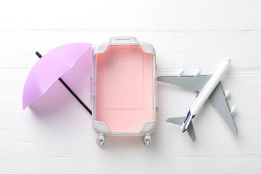 Seyahat sigortası. Uçak modeli, küçük şemsiye ve bavul beyaz ahşap masa, düz yatıyordu.