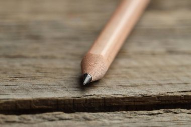 Tahta masada keskin bir grafit kalem, yakın plan.