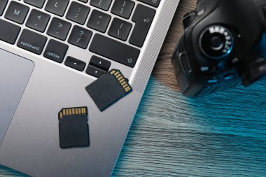 SD hafıza kartları, kamera ve laptop ahşap masada, düz yatıyordu.