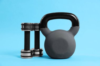 Açık mavi arkaplanda kettlebell ve dambıllar