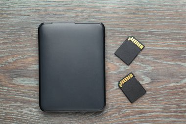 Sabit disk sürücüsü ve SD hafıza kartları gri ahşap tabloda, düz konum