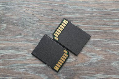 Gri ahşap masada iki SD hafıza kartı var.