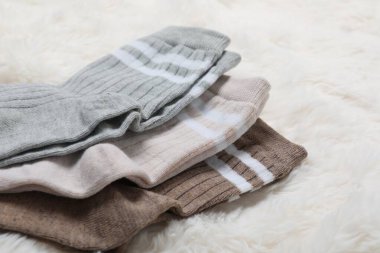 Beyaz sahte kürkte farklı yumuşak çoraplar, yakın plan.