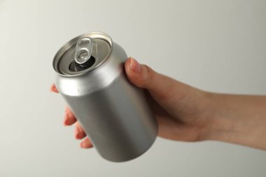 Açık gri arka planda teneke kutusu olan kadın, yakın plan.