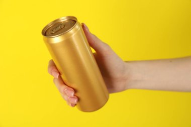 Sarı arka planda teneke kutusu olan kadın, yakın plan.