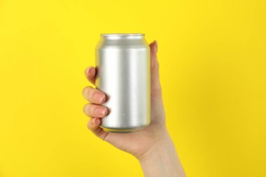 Sarı arka planda teneke kutusu olan kadın, yakın plan.