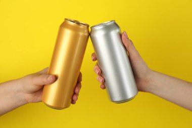 Sarı arka planda teneke kutuları olan kadınlar, yakın plan