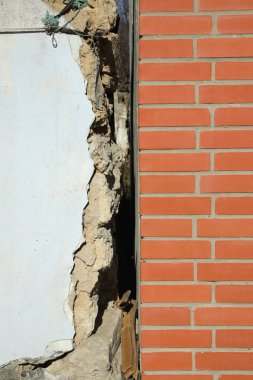 Yeni tuğla duvarın yanındaki eski beyaz bina. Deprem sonrası.