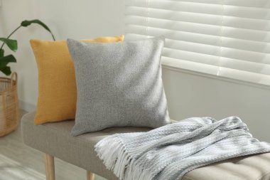 Odadaki kanepede yumuşak dekoratif yastıklar ve battaniye.