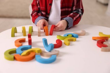 Motor beceri geliştirme. Beyaz masadaki oyuncaklarla oynayan küçük çocuk, yakın plan.