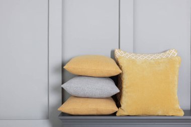 Gri duvarın yanındaki çekmecelerin üzerindeki yumuşak dekoratif yastıklar. Metin için boşluk