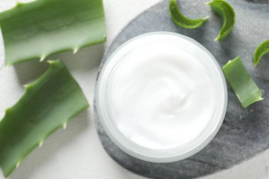 Beyaz arkaplanda krema ve aloe yaprakları düz.