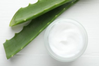 Beyaz ahşap zemin üzerinde krema ve aloe yaprakları, düz yatıyordu