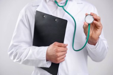 Steteskop ve arkaplanda pano olan doktor, yakın plan.