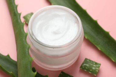 Kavanozda aloe vera özütüyle nemlendirici krem ve pembe arka planda yapraklar, yakın plan