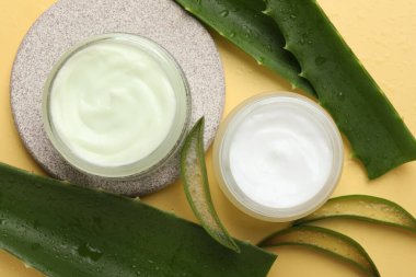 Aloe vera özütüyle nemlendirici krem ve sarı arka planda yapraklar.