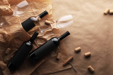 Şarap şişeleri, bardaklar, tirbuşon ve parşömen kağıdındaki mantarlar, düz yatak. Metin için boşluk