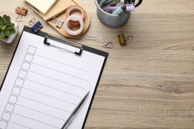 Kontrol listesi, farklı kırtasiye malzemeleri ve ahşap masa üzerindeki çiçek dekoru. Metin için boşluk