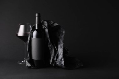 Bir şişe şarap, şarap kadehi ve siyah zemin üzerine kağıt, metin için boşluk